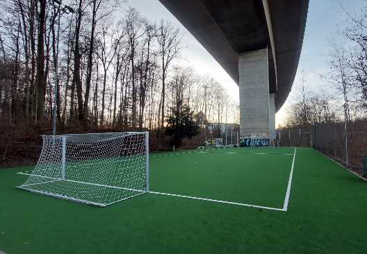 Kunstrasenfeld unter einer Brücke