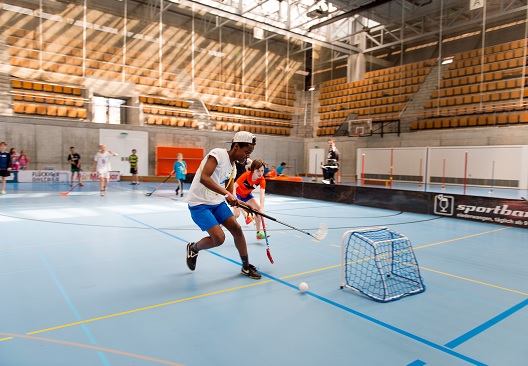 Kinder spielen Unihockey mit einem kleinen Tor in einer Turnhalle