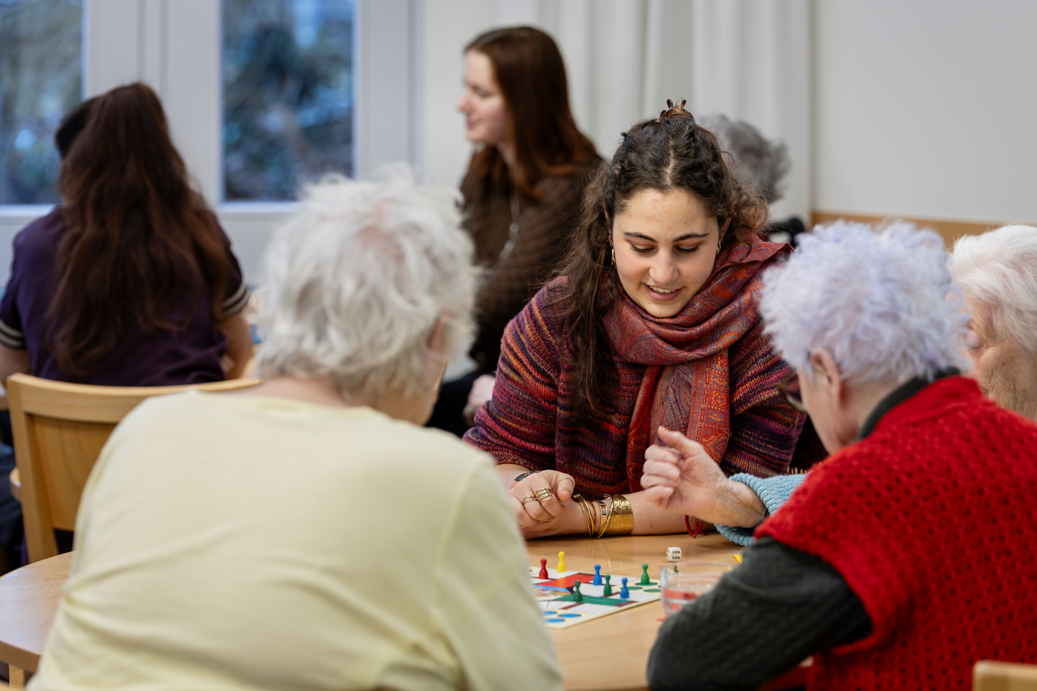 Junge Frau spielt Brettspiel mit älteren Frauen